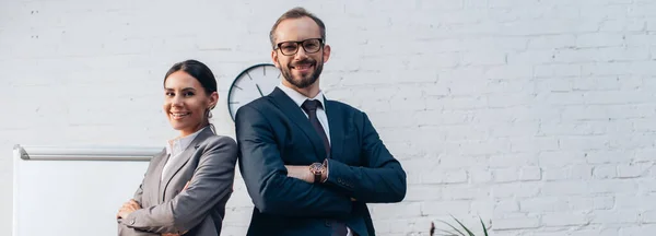 Horizontal concept of lawyers in suits standing with crossed arms and looking at camera in office — Stock Photo