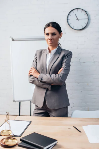 Brunette avocat en tenue formelle debout avec les bras croisés dans le bureau — Photo de stock