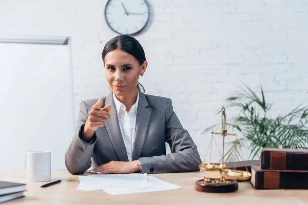 Brünette Rechtsanwältin in formeller Kleidung, die in die Kamera schaut und im Büro mit dem Finger zeigt — Stockfoto