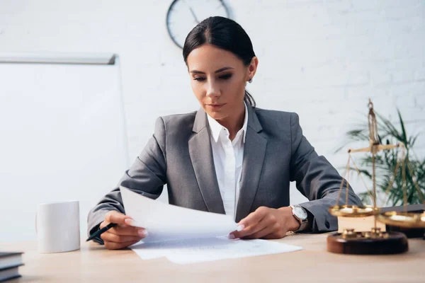 Selektiver Fokus der brünetten Anwältin in offizieller Kleidung beim Betrachten von Versicherungsunterlagen im Büro — Stockfoto