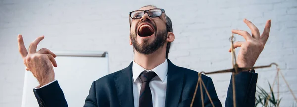 Imagen horizontal de abogado excitado y barbudo con la boca abierta mirando hacia arriba en la oficina - foto de stock