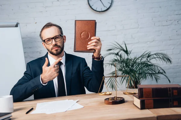 Selektiver Fokus des bärtigen Rechtsanwalts, der mit dem Finger auf Buch im Amt zeigt — Stockfoto