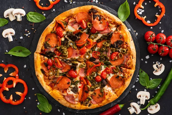 Vue de dessus de délicieuses pizzas italiennes avec légumes et salami sur fond noir — Photo de stock