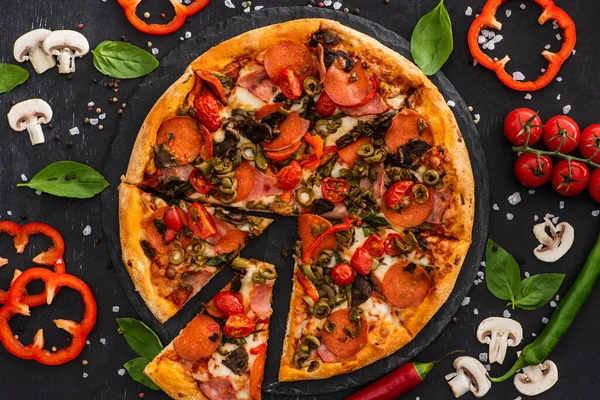 Vue de dessus de délicieuses pizzas italiennes avec légumes et salami sur fond noir — Photo de stock