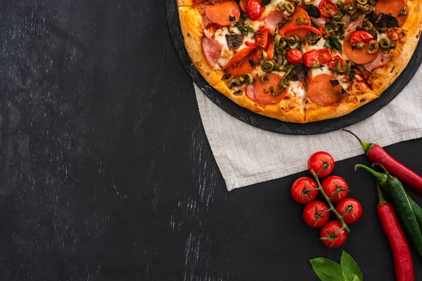 Vista superior de deliciosa pizza italiana com legumes e salame no fundo preto — Fotografia de Stock