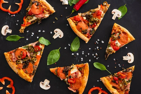 Vue de dessus de délicieuses tranches de pizza italienne avec des légumes et du salami sur fond noir — Photo de stock