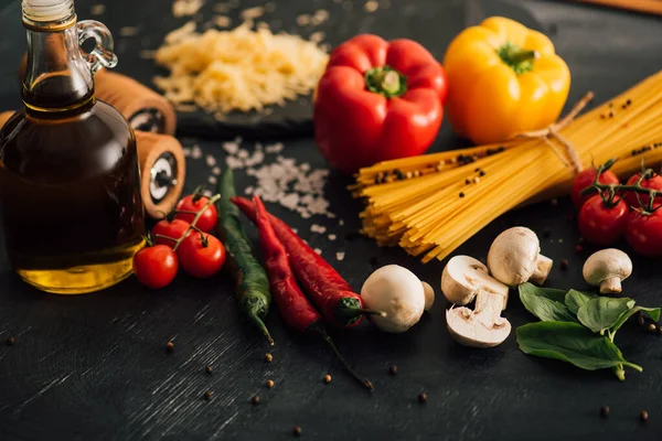 Foco seletivo de espaguete italiano cru com legumes no fundo preto — Fotografia de Stock