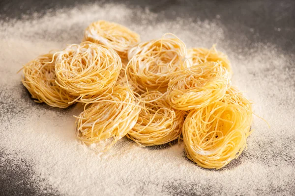 Capellini crudi italiani con farina su sfondo nero — Foto stock