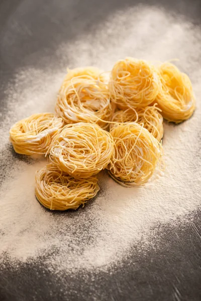 Raw Italian Capellini with flour on black background — Stock Photo
