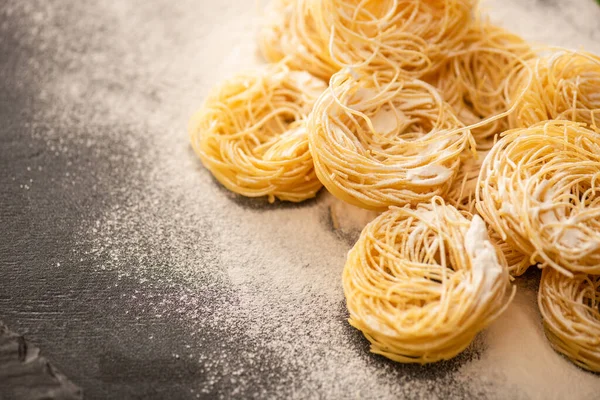 Raw Italian Capellini with flour on black background — Stock Photo