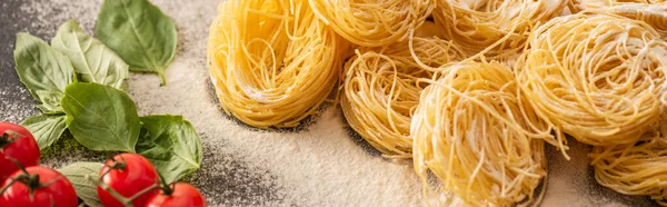 Capellini crudi italiani con verdure e farina su fondo nero, colpo panoramico — Foto stock
