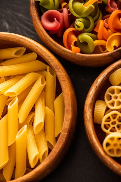 Close up view of various raw Italian pasta in wooden bowls — Stock Photo