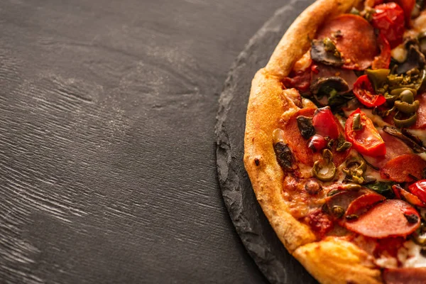 Vista superior de deliciosa pizza italiana com legumes e salame em fundo de madeira preta — Fotografia de Stock