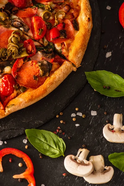 Close up view of delicious Italian pizza with vegetables and salami on black background — Stock Photo