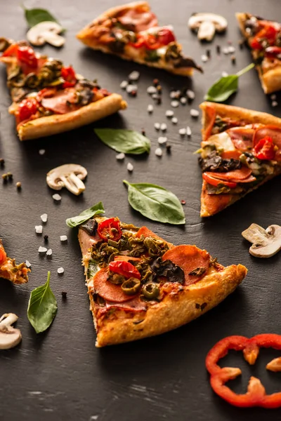 Foco seletivo de deliciosas fatias de pizza italiana com salame perto de legumes no fundo preto — Stock Photo