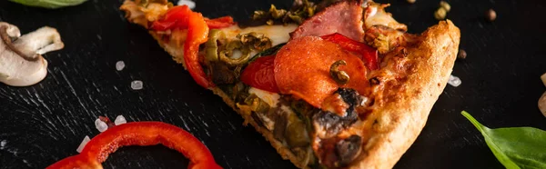 Deliciosa rebanada de pizza italiana con salami sobre fondo negro, plano panorámico - foto de stock