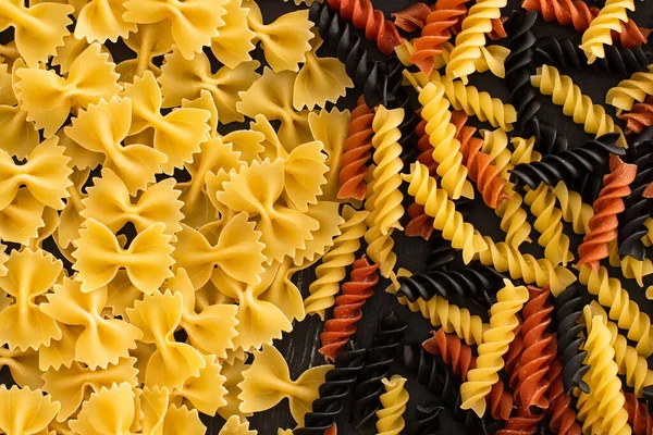 Vue de dessus des pâtes fusilli et farfalle colorées crues — Photo de stock