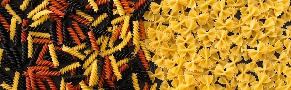 Vue de dessus des pâtes fusilli et farfalle colorées crues, vue panoramique — Photo de stock