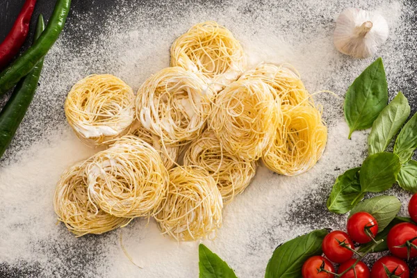 Von oben auf rohe Capellini-Pasta mit Gemüse und Mehl — Stockfoto