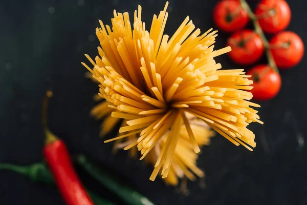 Selective focus of raw Italian spaghetti and vegetables isolated on black — Stock Photo