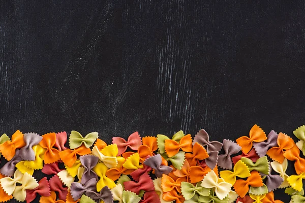 Вид сверху на красочный сырой фарфоровой макароны на черном деревянном фоне — стоковое фото