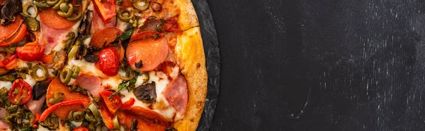 Top view of delicious Italian pizza with salami on black wooden background, panoramic shot — Stock Photo