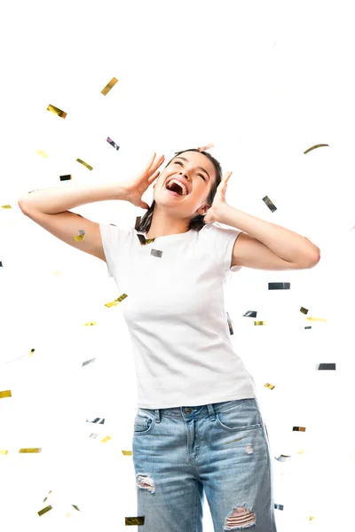 Mujer excitada en camiseta blanca gestos cerca de confeti en blanco - foto de stock