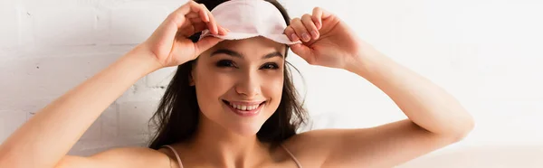 Horizontal crop of young woman touching pink eye mask — Stock Photo