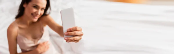 Panoramic shot of pregnant young woman taking selfie in bedroom — Stock Photo
