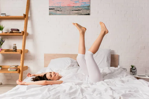 Young and barefoot woman lying on bed at home — Stock Photo