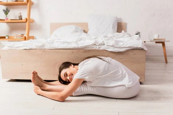 Barefoot woman with closed eyes stretching on floor — Stock Photo