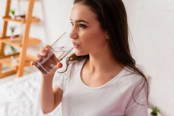 Giovane donna bruna che beve acqua fresca a casa — Foto stock