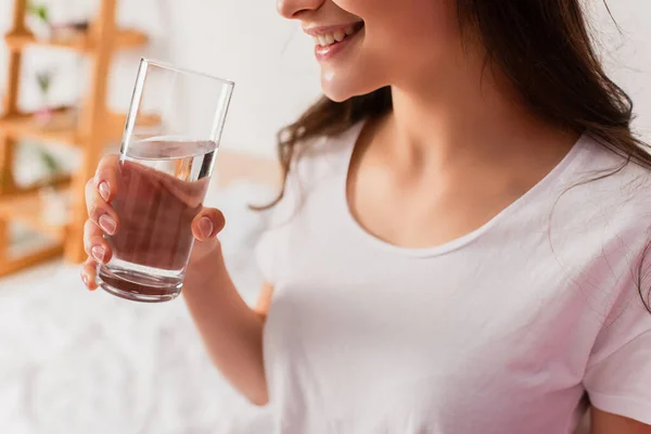 Abgeschnittene Ansicht einer jungen brünetten Frau mit einem Glas Wasser — Stockfoto
