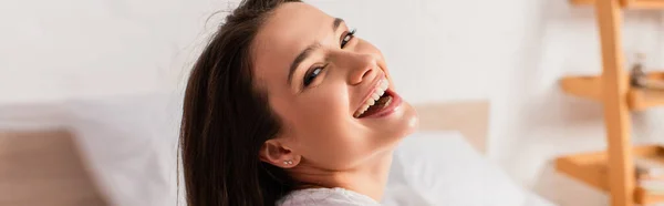 Panoramic crop of young and brunette woman looking at camera at home — Stock Photo