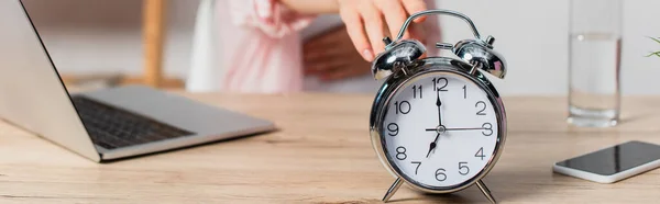 Panoramic crop of retro alarm clock near freelancer and gadgets on table — Stock Photo