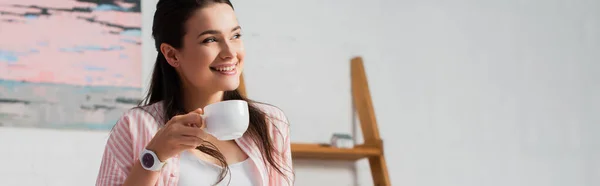 Horizontal crop of woman looking away while holding cup of coffee — Stock Photo