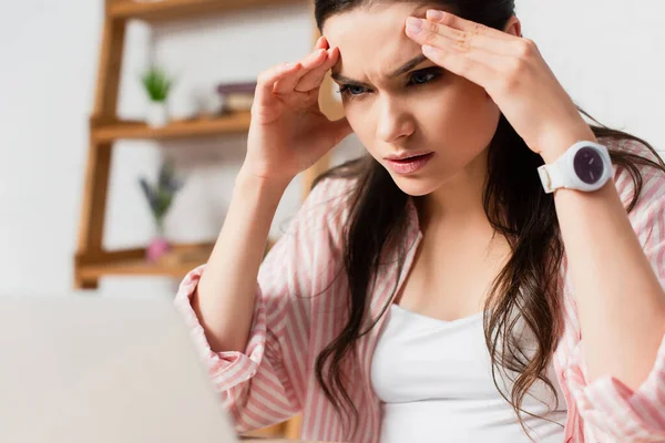 Selective focus of tired woman touching head at home — Stock Photo