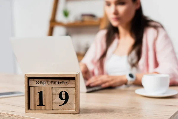 Selective focus of wooden cubes with date near freelancer working from home — Stock Photo