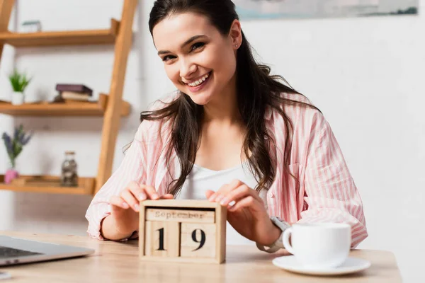 Selective focus of woman touching wooden cubes with date near cup of coffee — Stock Photo