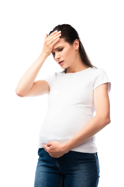 Измученная беременная женщина в белой футболке касается головы, изолированной на белом — стоковое фото