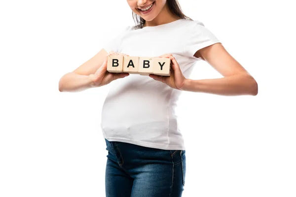 Частичный вид молодой беременной женщины в белой футболке, держащей деревянные кубики с детскими надписями, изолированными на белом — стоковое фото