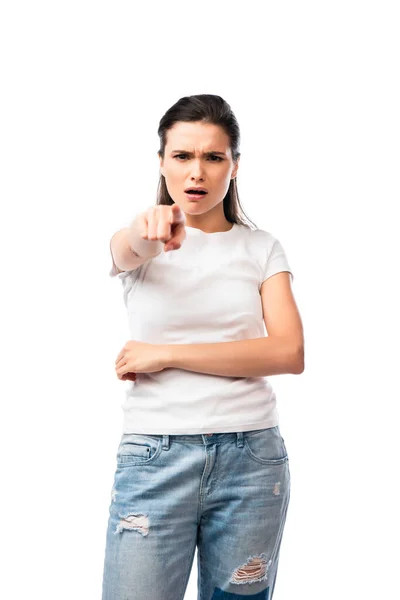 Foco seletivo de mulher jovem descontente em t-shirt branca e jeans apontando com o dedo isolado no branco — Fotografia de Stock