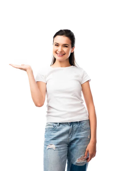 Молодая женщина в белой футболке и джинсах указывая рукой изолированы на белом — стоковое фото