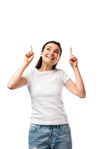 Brunette woman in white t-shirt pointing with fingers and looking up isolated on white — Stock Photo