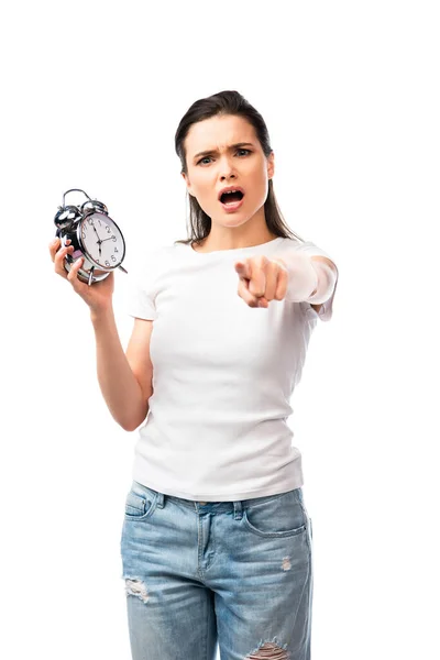 Selective focus of woman in white t-shirt and jeans holding retro alarm clock while pointing with finger isolated on white — Stock Photo