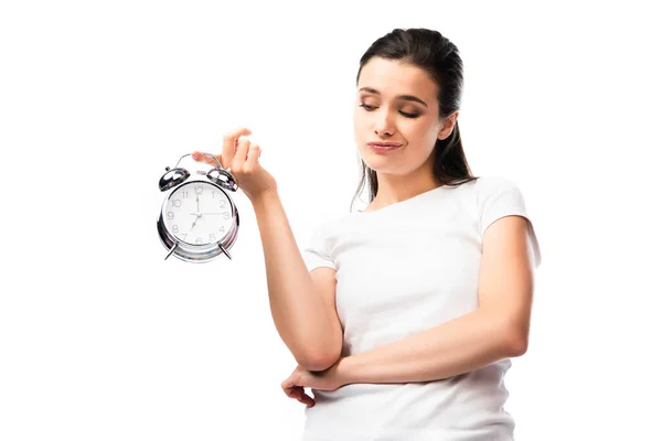 Dissatisfied woman in white t-shirt looking at retro alarm clock isolated on white — Stock Photo