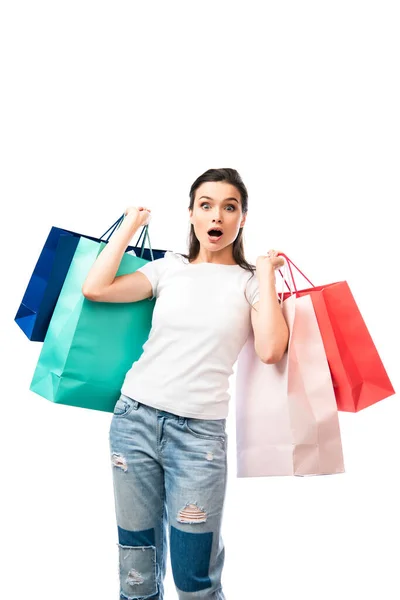 Mujer conmocionada sosteniendo bolsas de compras y mirando a la cámara aislada en blanco - foto de stock