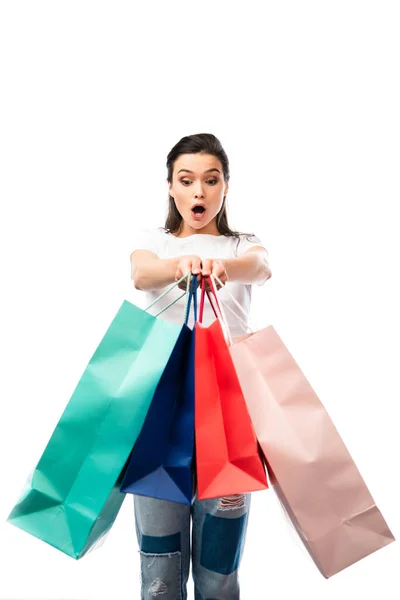 Mulher chocada olhando para sacos de compras isolados em branco — Fotografia de Stock
