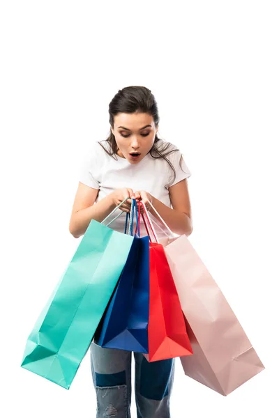 Giovane donna scioccata guardando borse della spesa isolate su bianco — Foto stock