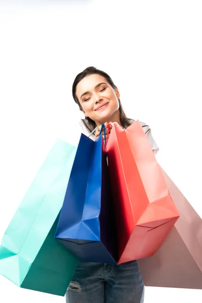 Junge brünette Frau mit geschlossenen Augen, die Einkaufstüten isoliert auf weiß hält — Stockfoto